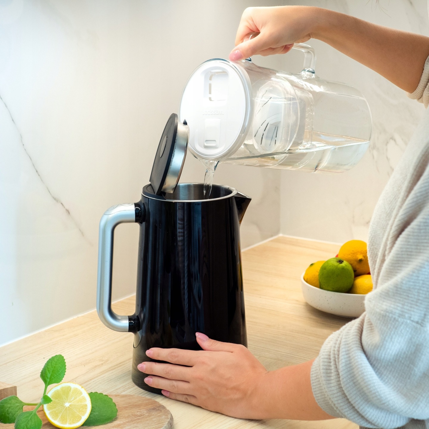 Kobieta nalewa wodę z dzbanka Wessper D2 do czajnika